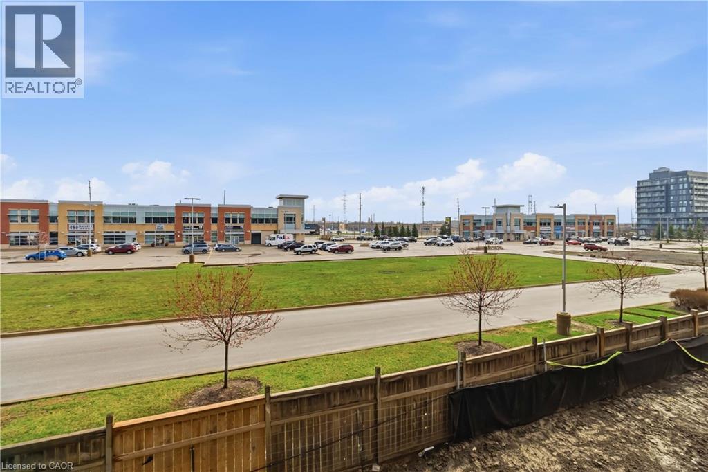 The property offers views of commercial buildings with varied facades, a parking area, and green spaces - 4878 Powers Common Unit# 224, Burlington, ON - Outdoor With View