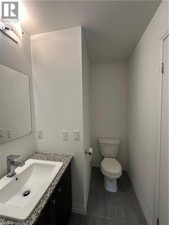 The bathroom features a modern vanity with a granite countertop, a white rectangular sink, and a chrome faucet - 108 Garment Street S Unit# 708, Kitchener, ON - Indoor Photo Showing Bathroom