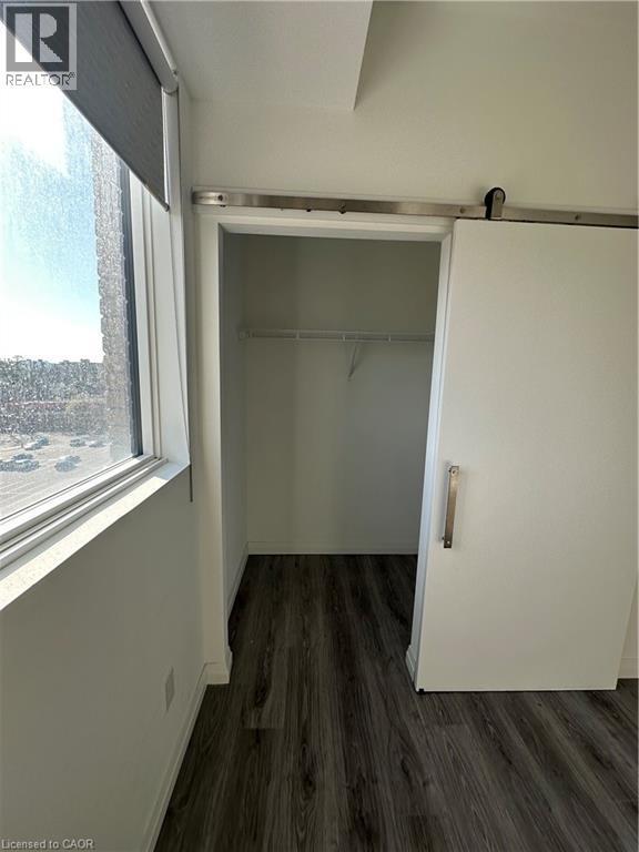 This property features durable wood-look flooring, a large window with a roller blind, and a barn-style sliding door - 108 Garment Street S Unit# 708, Kitchener, ON - Indoor