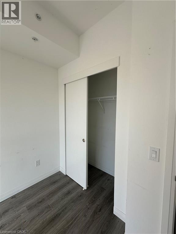 Room featuring dark wood-style flooring, white walls, and a closet with sliding doors - 108 Garment Street S Unit# 708, Kitchener, ON - Indoor Photo Showing Other Room