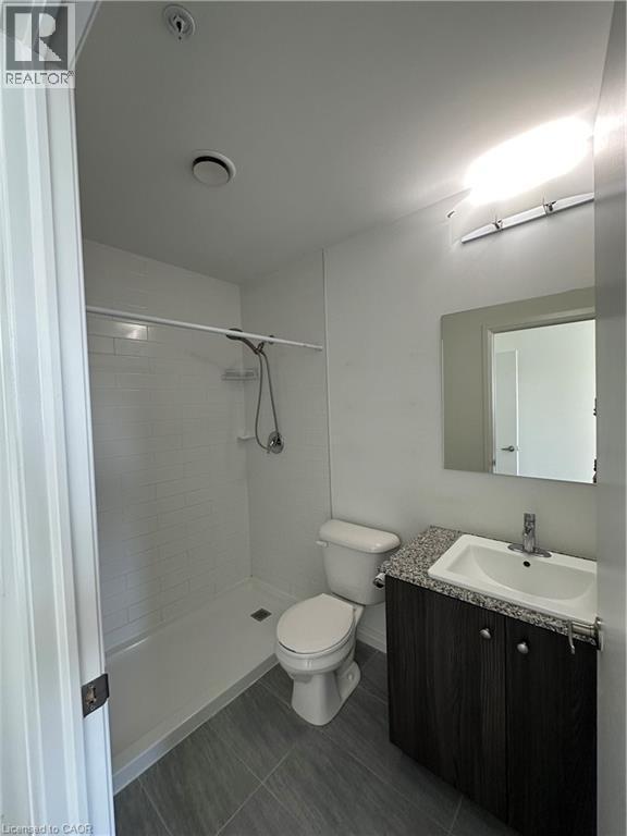 The bathroom features a walk-in shower with white subway tile, a vanity with a granite countertop and dark wood cabinetry, and tiled flooring - 108 Garment Street S Unit# 708, Kitchener, ON - Indoor Photo Showing Bathroom