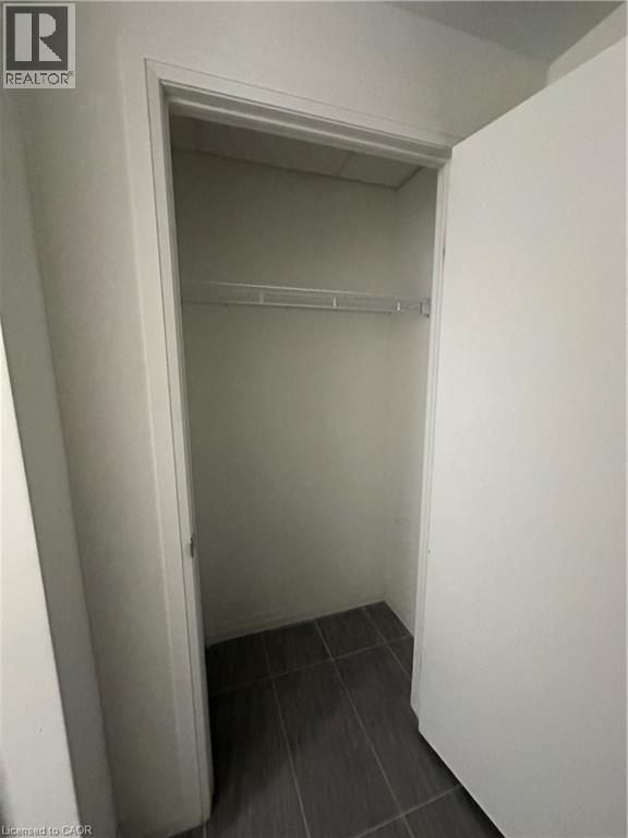 This property features a closet with a wire shelf and dark tiled flooring - 108 Garment Street S Unit# 708, Kitchener, ON - Indoor
