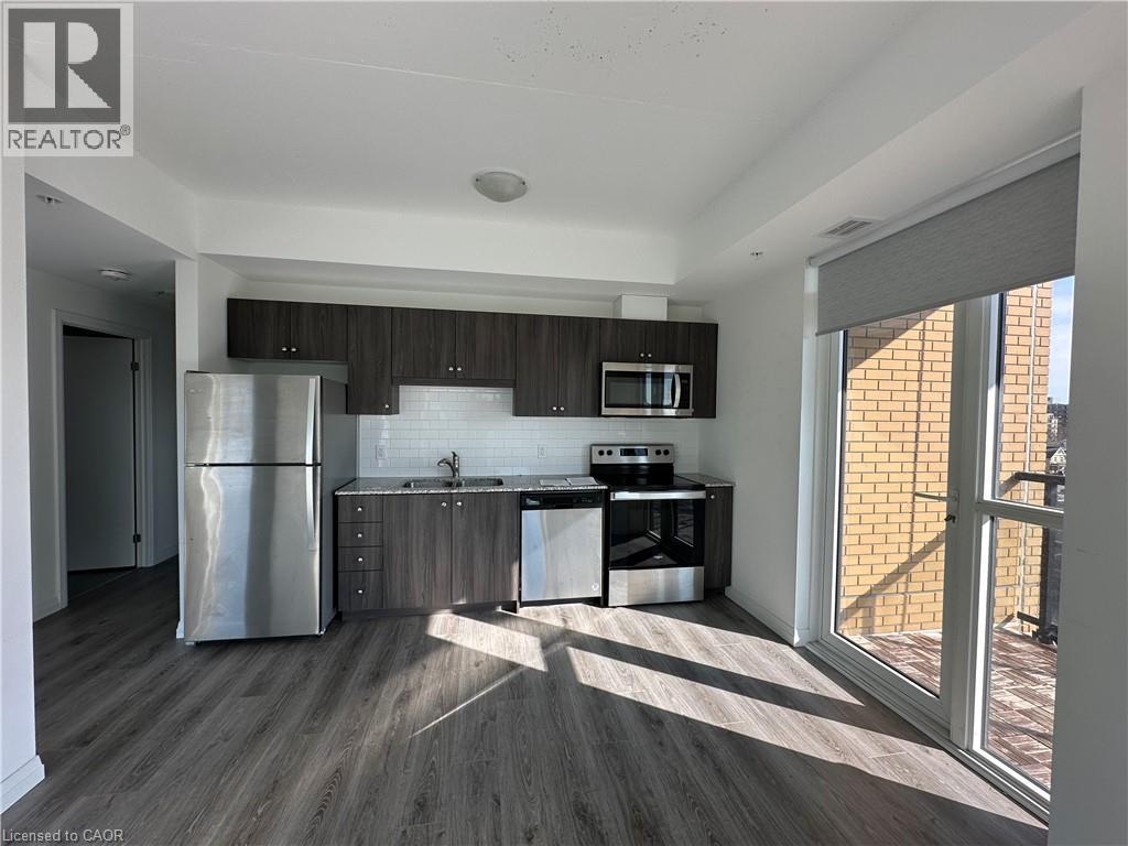 This property features a kitchen with stainless steel appliances, dark wood-style cabinetry, and a white subway tile backsplash - 108 Garment Street S Unit# 708, Kitchener, ON - Indoor Photo Showing Kitchen