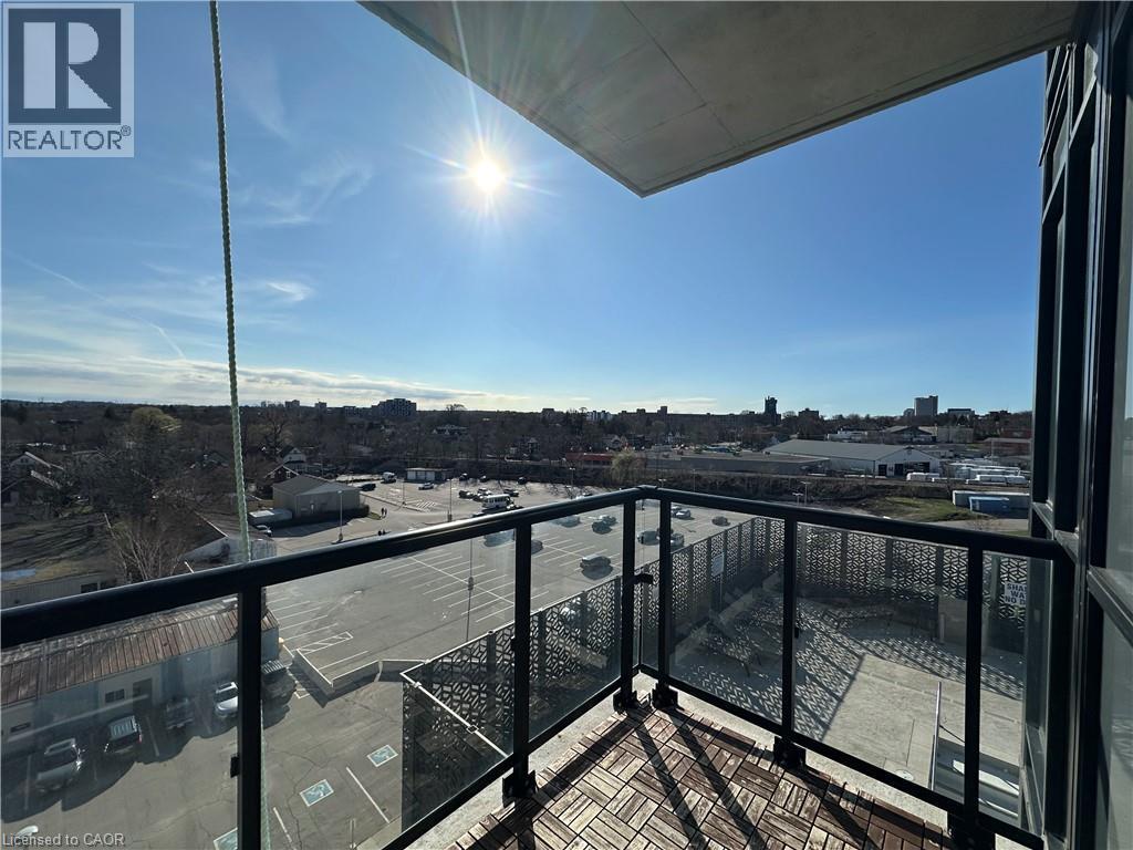 The property features a balcony with glass railings and wood tile flooring, offering expansive views of the surrounding urban landscape and a clear sky - 108 Garment Street S Unit# 708, Kitchener, ON - Outdoor With View With Exterior