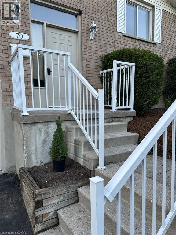 The property features a brick exterior with white window shutters and a light-colored main entry door with an overhead transom window - 70 Bechtel Drive, Kitchener, ON - Outdoor With Exterior