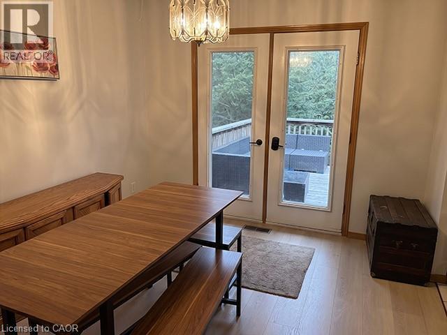 French doors opening to an exterior deck, featuring a decorative overhead light fixture, light wood-finish flooring, and white wall finishes - 70 Bechtel Drive, Kitchener, ON - Indoor Photo Showing Dining Room