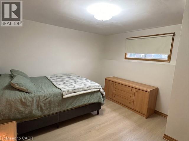 Room featuring light wood-finish flooring, a window with wood trim, and a flush-mount ceiling light fixture - 70 Bechtel Drive, Kitchener, ON - Indoor Photo Showing Bedroom