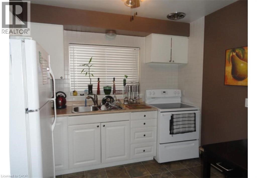 The kitchen features white cabinetry, a white refrigerator, and a white electric range - 981 Mohawk Road E, Hamilton, ON - Indoor Photo Showing Kitchen With Double Sink