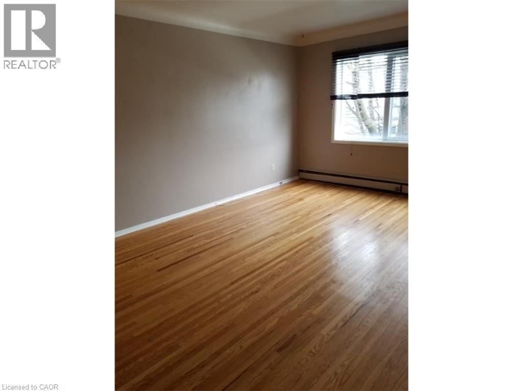 This room features hardwood flooring, neutral-toned walls, and a window with blinds - 981 Mohawk Road E, Hamilton, ON - Indoor Photo Showing Other Room