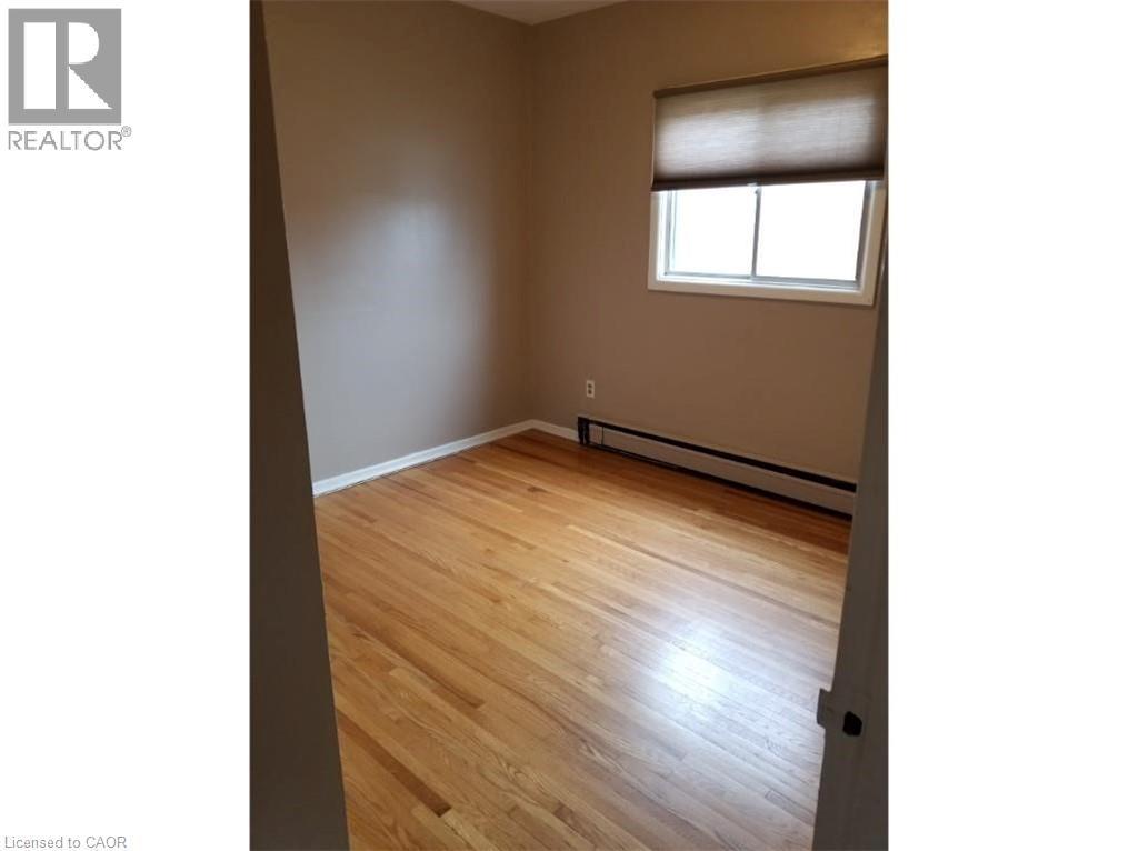Room featuring hardwood floors, a window with a shade, and baseboard heating - 981 Mohawk Road E, Hamilton, ON - Indoor Photo Showing Other Room