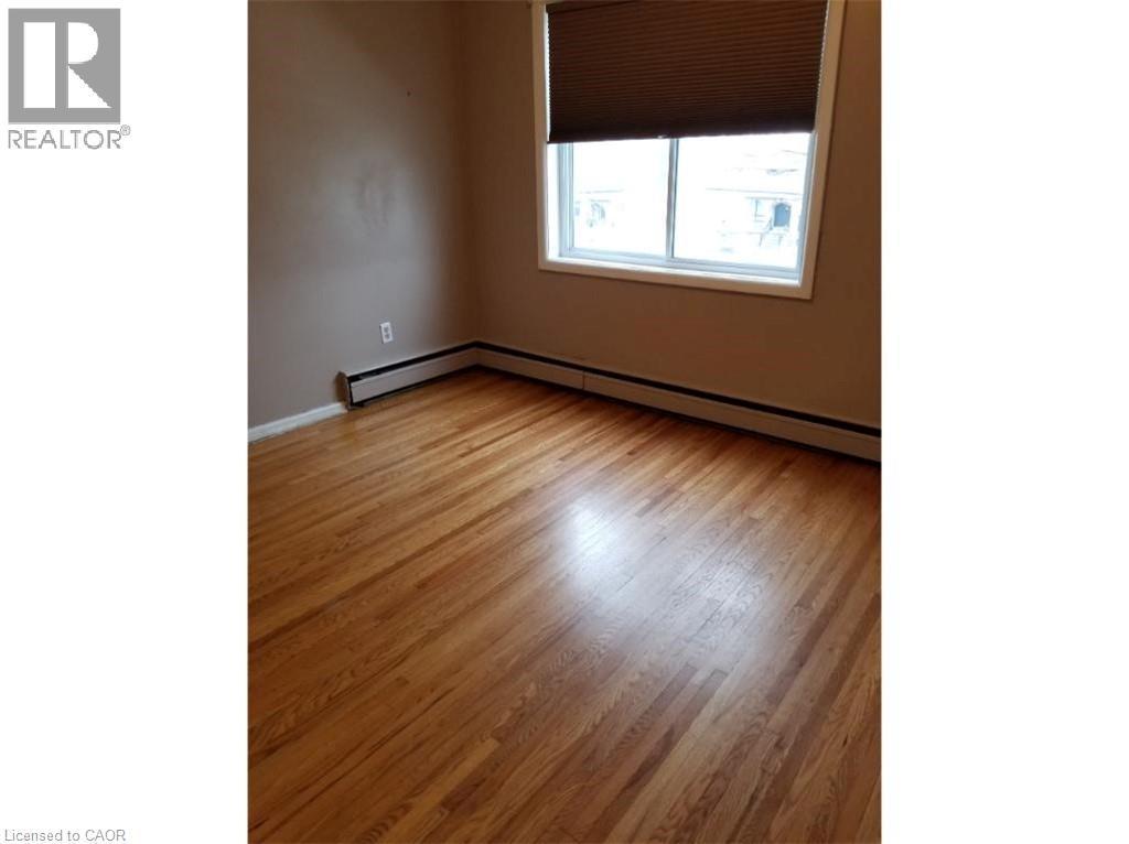 Room featuring hardwood floors, a window with blinds, and baseboard heating - 981 Mohawk Road E, Hamilton, ON - Indoor Photo Showing Other Room