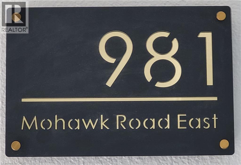 The property features a sleek black address plaque with gold-toned numbers and lettering - 981 Mohawk Road E, Hamilton, ON -