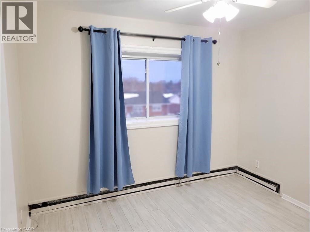 The room features light-colored walls, a window with curtains, and a ceiling fan with integrated lighting - 981 Mohawk Road E, Hamilton, ON - Indoor Photo Showing Other Room
