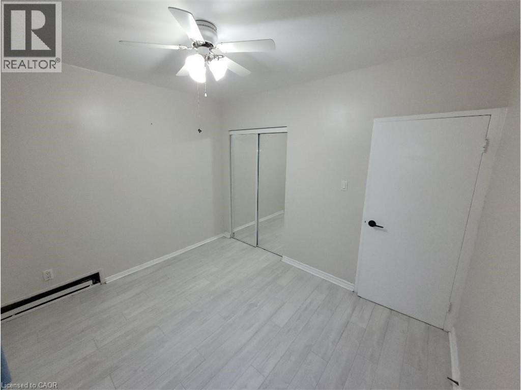 This room features light-colored flooring, a ceiling fan with integrated lighting, and a closet with mirrored sliding doors - 981 Mohawk Road E, Hamilton, ON - Indoor Photo Showing Other Room