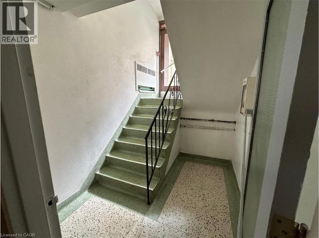 The property features a staircase with light green treads and risers, complemented by a black metal railing - 981 Mohawk Road E, Hamilton, ON - Indoor Photo Showing Other Room