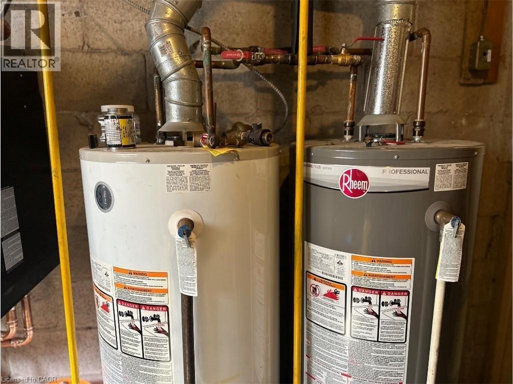 The property features two water heaters, one white and one gray, with visible piping and ductwork - 981 Mohawk Road E, Hamilton, ON - Indoor Photo Showing Basement