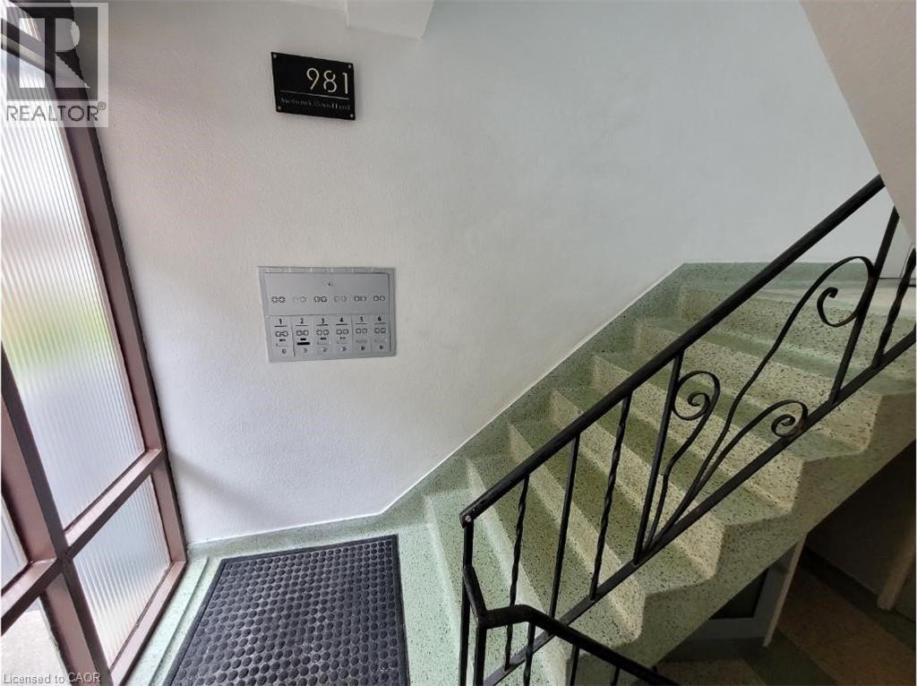 The property features a staircase with a black metal railing and light green speckled steps - 981 Mohawk Road E, Hamilton, ON - Indoor Photo Showing Other Room