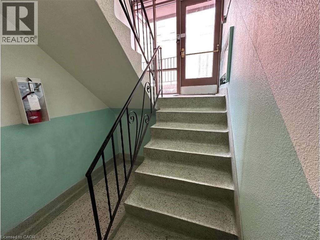 Stairwell featuring terrazzo steps, black wrought iron railings, and a two-toned wall - 981 Mohawk Road E, Hamilton, ON - Indoor Photo Showing Other Room