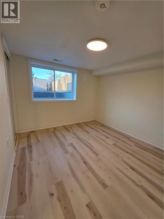 This room features light-toned hardwood flooring, a window offering natural light, and recessed lighting - 62 Richwill Road Unit# Lower, Hamilton, ON - Indoor Photo Showing Other Room