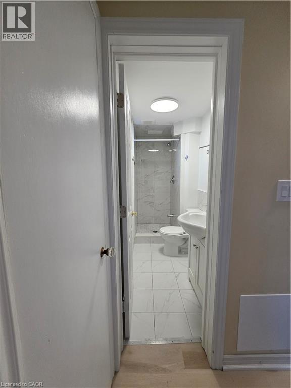 The bathroom features a toilet, a vanity with an integrated sink, and a shower with a glass enclosure - 62 Richwill Road Unit# Lower, Hamilton, ON - Indoor Photo Showing Bathroom