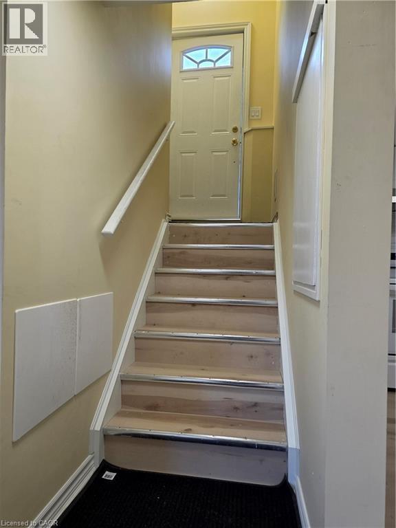 Staircase with light wood treads and a white handrail, leading to an entry door with a decorative glass insert - 62 Richwill Road Unit# Lower, Hamilton, ON - Indoor Photo Showing Other Room