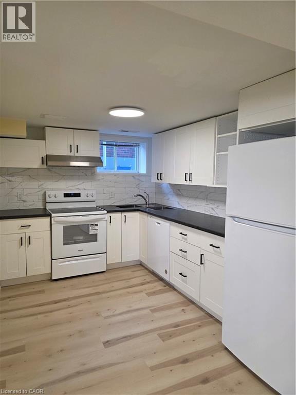 The kitchen features white cabinetry, dark countertops, and a white tile backsplash - 62 Richwill Road Unit# Lower, Hamilton, ON - Indoor Photo Showing Kitchen