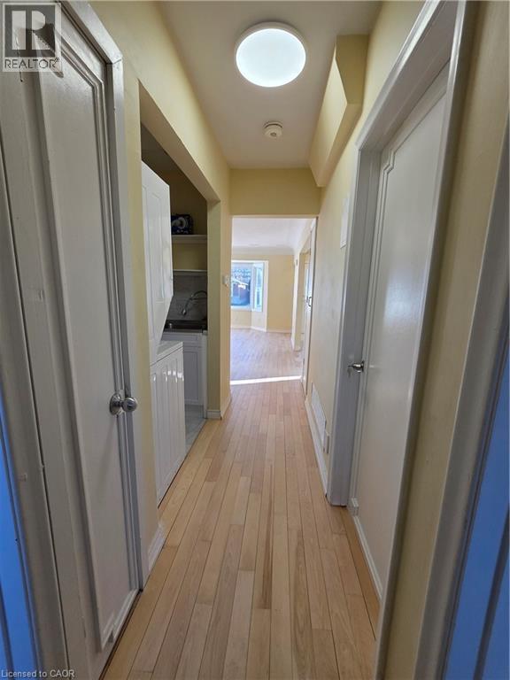 Hallway featuring light-toned wood flooring, a ceiling-mounted light fixture, and white doors with silver-toned hardware - 62 Richwill Road Unit# Upper, Hamilton, ON - Indoor Photo Showing Other Room