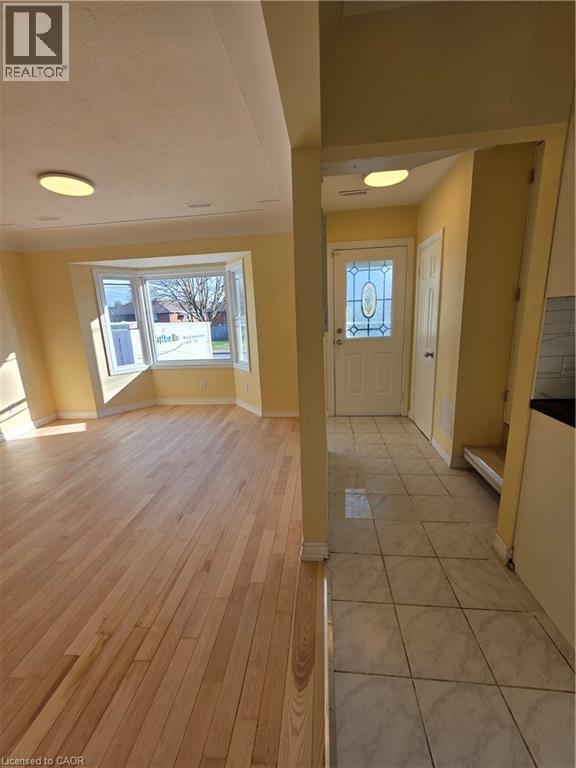 The property features hardwood floors and a bay window in the main living area, complemented by a tiled entryway with a decorative glass front door - 62 Richwill Road Unit# Upper, Hamilton, ON - Indoor Photo Showing Other Room