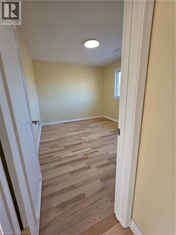 This room features light-colored walls and wood flooring, complemented by a round ceiling light fixture - 62 Richwill Road Unit# Upper, Hamilton, ON - Indoor Photo Showing Other Room