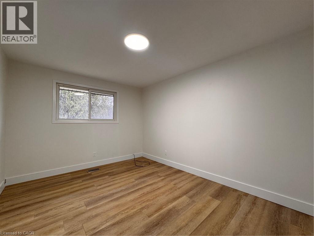 This room features light wood-style flooring, a window offering natural light, and a circular ceiling light fixture - 23 Arrowhead Crescent Unit# Upper, Kitchener, ON - Indoor Photo Showing Other Room