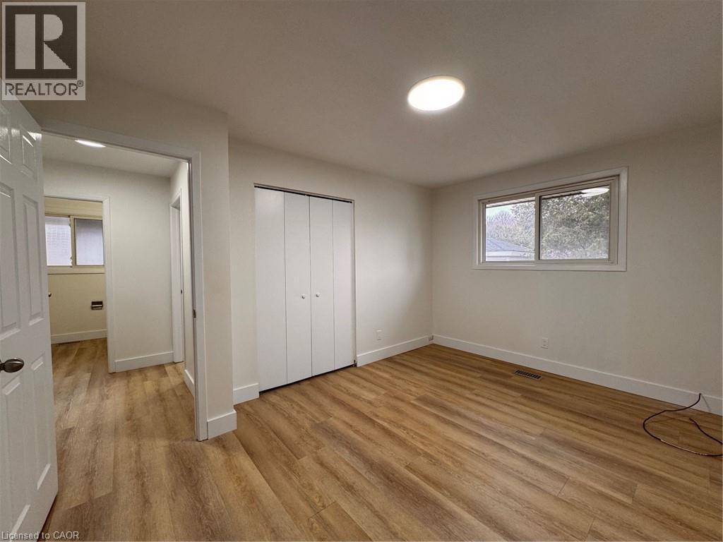 This room features wood flooring, a window providing natural light, and a closet with bifold doors - 23 Arrowhead Crescent Unit# Upper, Kitchener, ON - Indoor Photo Showing Other Room