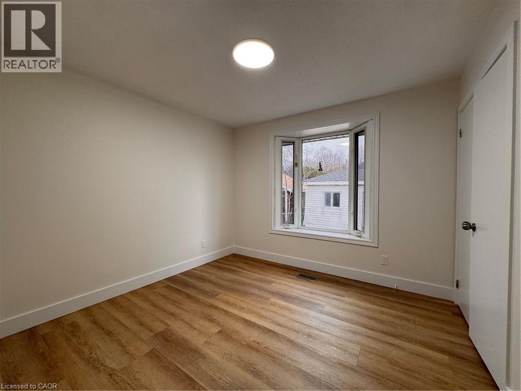 The interior space features light-colored walls, hardwood flooring, and a contemporary ceiling light fixture - 23 Arrowhead Crescent Unit# Upper, Kitchener, ON - Indoor Photo Showing Other Room