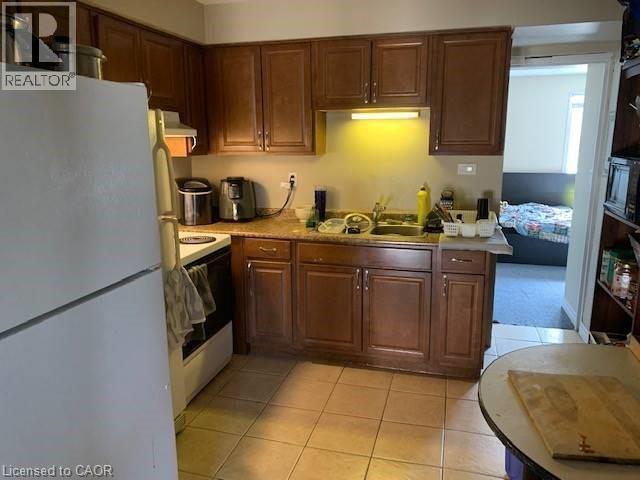 Kitchen featuring white appliances, light countertops, light tile patterned floors, and exhaust hood - 65 Cardill Crescent Unit# A, Waterloo, ON - Indoor Photo Showing Kitchen