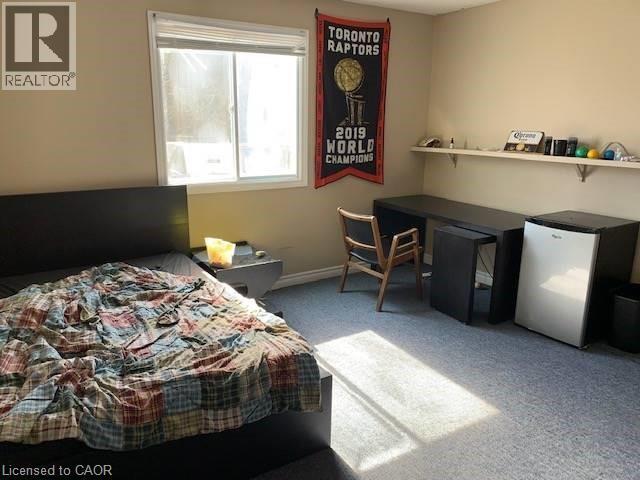 Bedroom with light carpet, freestanding refrigerator, and an office area - 65 Cardill Crescent Unit# A, Waterloo, ON - Indoor Photo Showing Bedroom