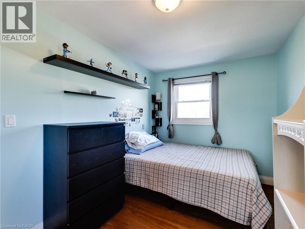 Hardwood-finish flooring, built-in shelving, white trim window, neutral ceiling light fixture - 9183 Silver Street, Caistor Centre, ON - Indoor Photo Showing Bedroom