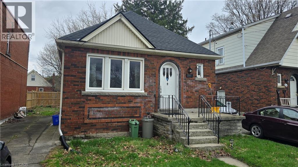The property features a brick exterior, a driveway, and a front yard with a walkway leading to the front entrance - 66 Cline Avenue Unit# Main Floor, Hamilton, ON - Outdoor With Exterior