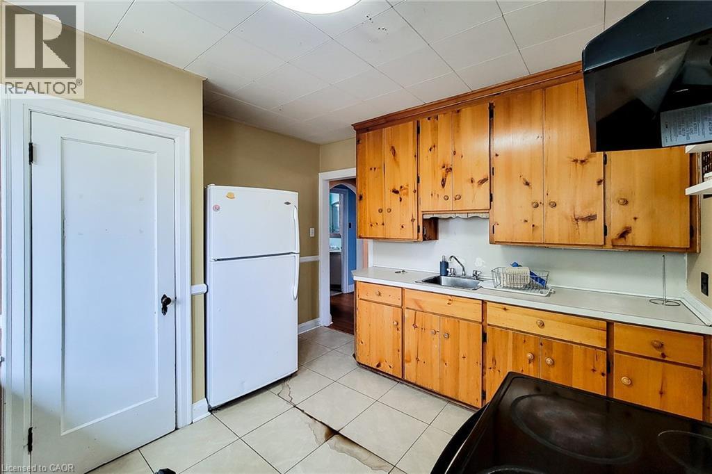 Kitchen featuring wood cabinetry, a stainless steel sink, and light-toned countertops - 66 Cline Avenue Unit# Main Floor, Hamilton, ON - Indoor Photo Showing Kitchen