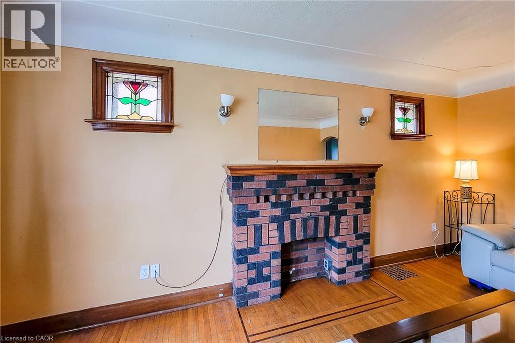 Brick fireplace with a wood-finish mantel, flanked by two wall sconces and two stained-glass windows - 66 Cline Avenue Unit# Main Floor, Hamilton, ON - Indoor Photo Showing Other Room