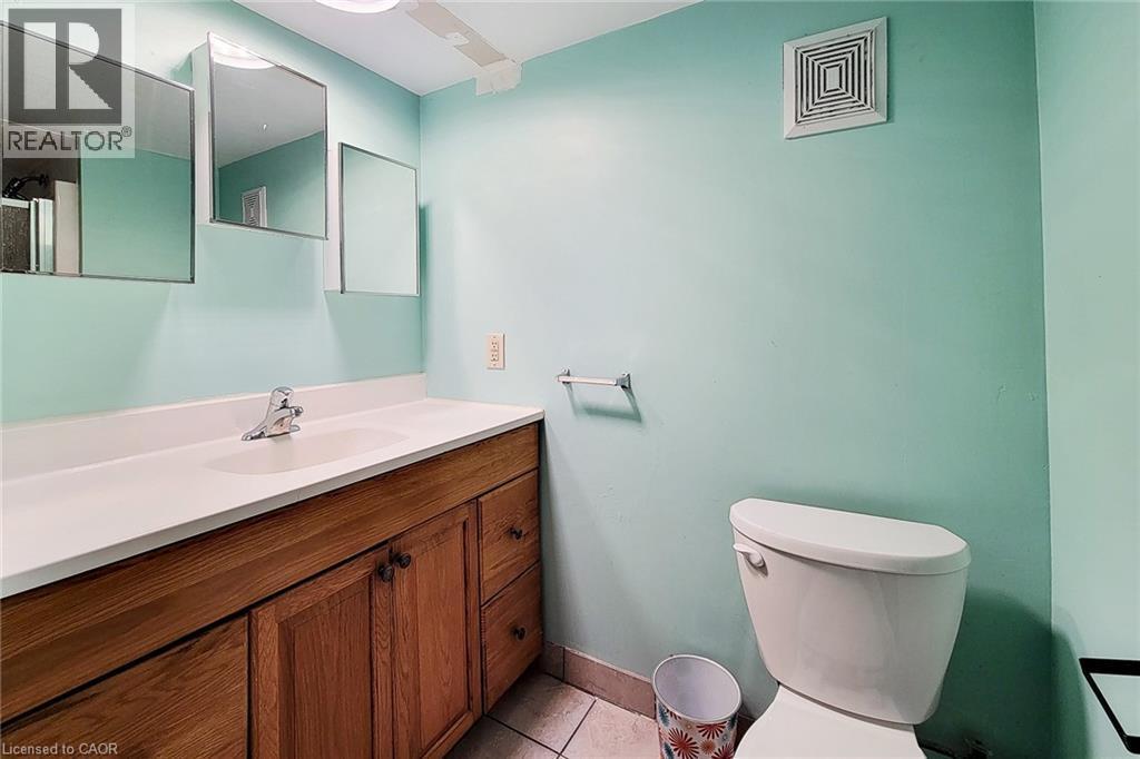 Bathroom vanity featuring a white countertop, an integrated sink, and wood-finish cabinetry with multiple doors and drawers - 66 Cline Avenue Unit# Main Floor, Hamilton, ON - Indoor Photo Showing Bathroom