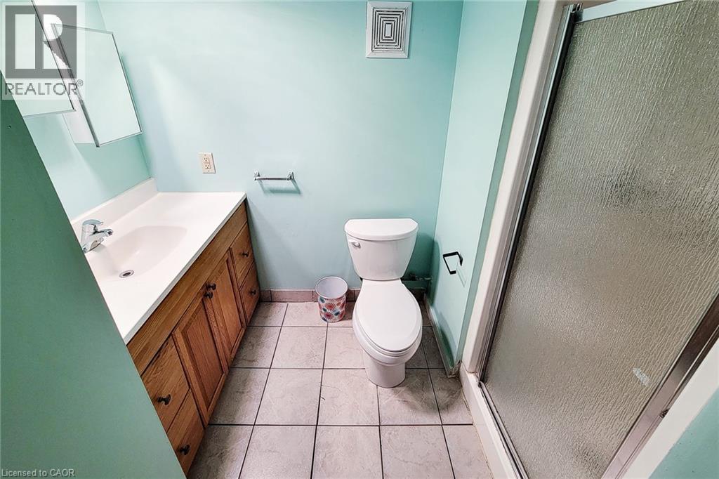 Full bathroom featuring a single vanity with wood-finish cabinetry, a white countertop, and an integrated sink - 66 Cline Avenue Unit# Main Floor, Hamilton, ON - Indoor Photo Showing Bathroom
