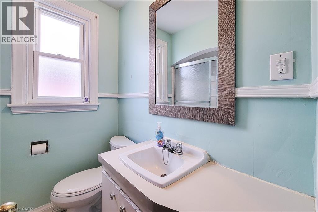 Bathroom featuring a vanity with an integrated sink and laminate countertop, a toilet, and a window with frosted lower pane - 66 Cline Avenue Unit# Main Floor, Hamilton, ON - Indoor Photo Showing Bathroom