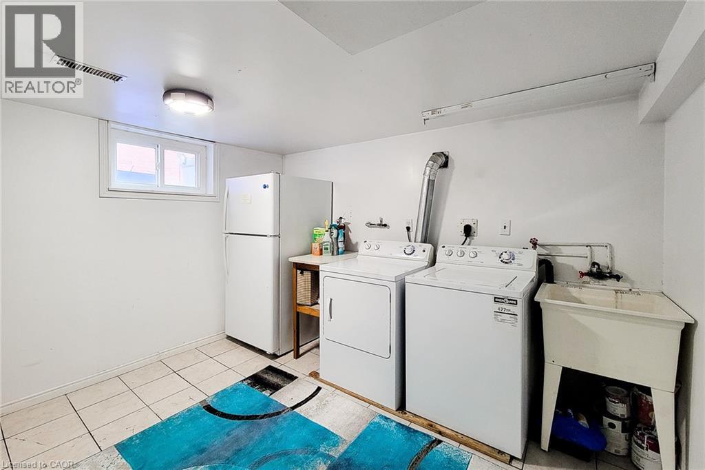Laundry area featuring a utility sink, a window, and tiled flooring - 66 Cline Avenue Unit# Main Floor, Hamilton, ON - Indoor Photo Showing Laundry Room