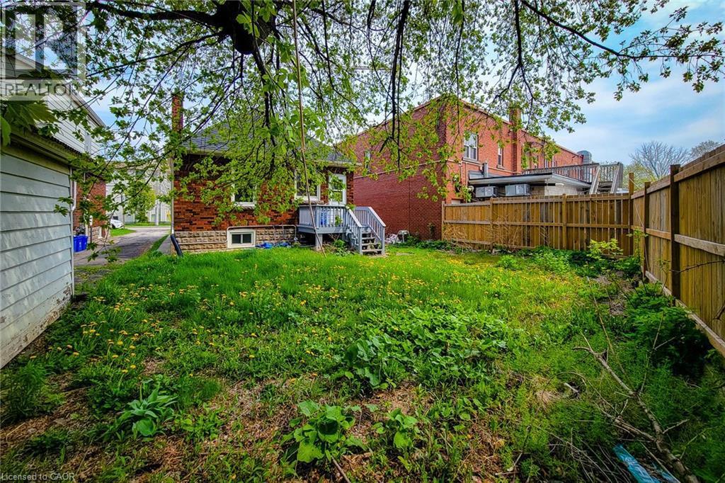 Expansive green space featuring perimeter fencing and a rear deck - 66 Cline Avenue Unit# Main Floor, Hamilton, ON - Outdoor