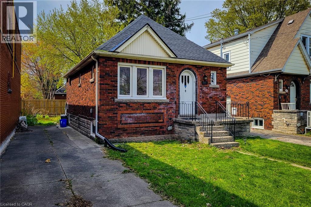 Brick exterior with a peaked roofline, featuring a front entry with an arched doorway and white door - 66 Cline Avenue Unit# Main Floor, Hamilton, ON - Outdoor