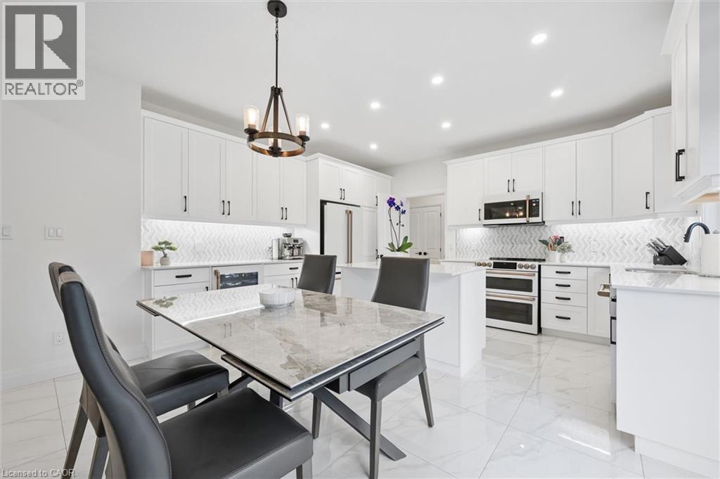 Bright kitchen featuring white cabinetry, stainless steel appliances, a white herringbone tile backsplash, and recessed lighting - 213 Fallowfield Drive, Kitchener, ON - Indoor