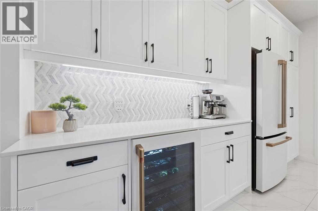 White cabinetry with black hardware, white countertops, and a chevron pattern tile backsplash - 213 Fallowfield Drive, Kitchener, ON - Indoor Photo Showing Kitchen
