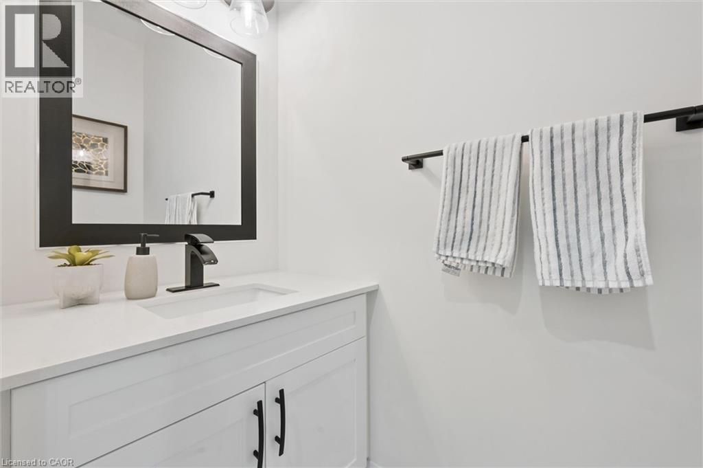 White vanity with shaker-style cabinetry, black hardware, and an integrated rectangular sink - 213 Fallowfield Drive, Kitchener, ON - Indoor Photo Showing Bathroom