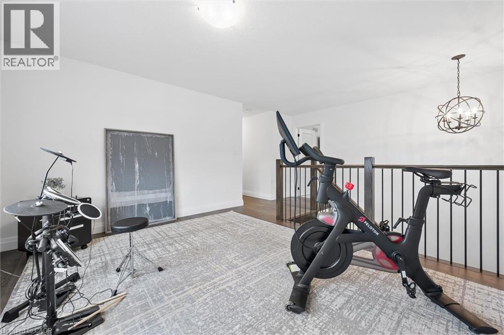 Open concept room featuring white walls, dark wood-finish flooring, and a modern light gray area rug - 213 Fallowfield Drive, Kitchener, ON - Indoor Photo Showing Gym Room