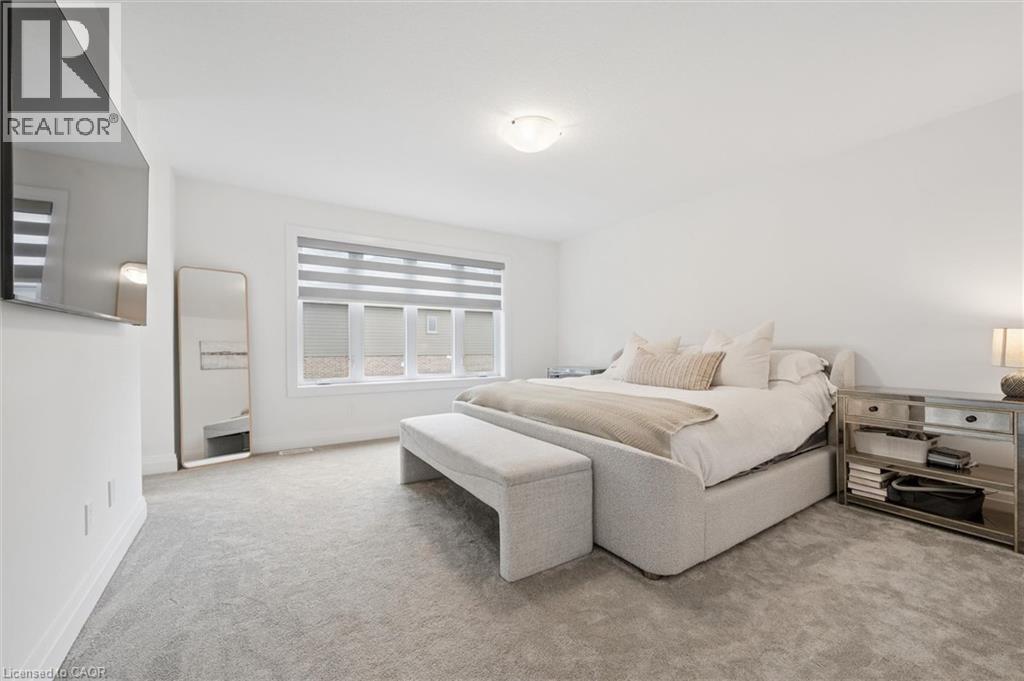 Carpeted bedroom with a large window featuring horizontal blinds - 213 Fallowfield Drive, Kitchener, ON - Indoor Photo Showing Bedroom