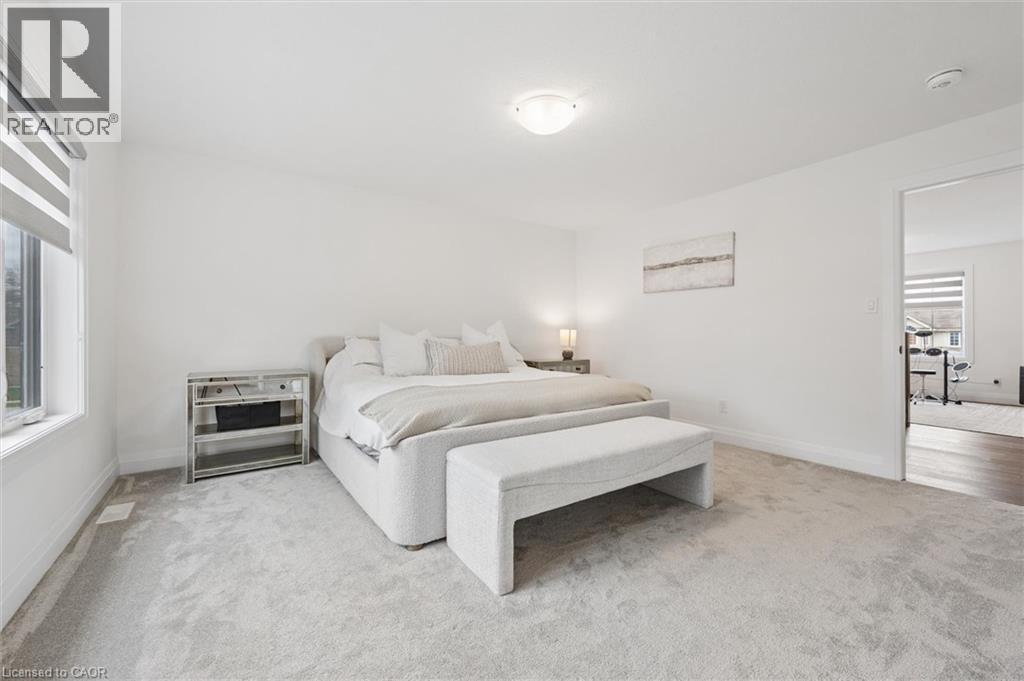 Carpeted bedroom with a window featuring roller blinds, white walls, and a ceiling-mounted light fixture - 213 Fallowfield Drive, Kitchener, ON - Indoor Photo Showing Bedroom